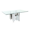 slightly right facing view of a dining table with a clear glass top and a unique geometric steel base.