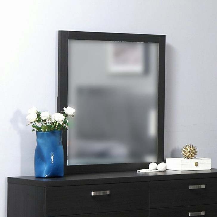dark wood mirror styled on top of matching mirror, decorative items, and a blue vase with flowers