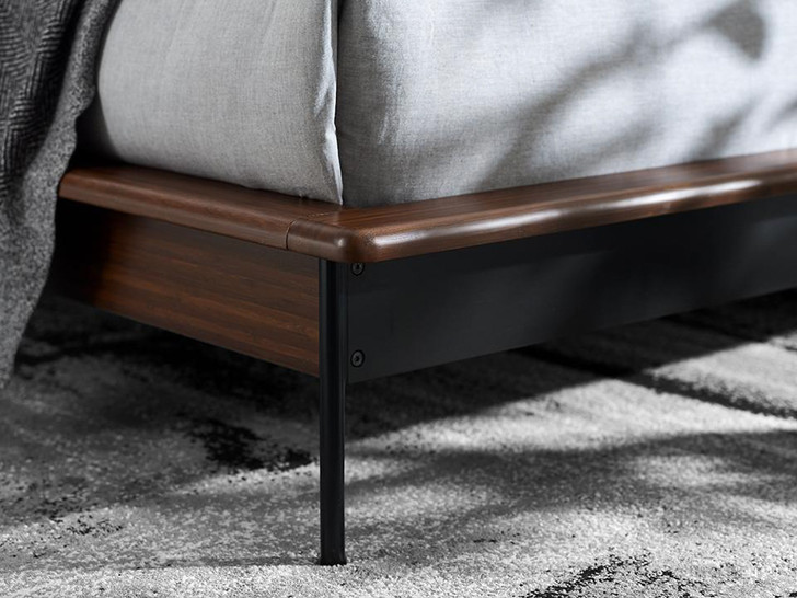 close up of bed foundation with dark wood and steel legs